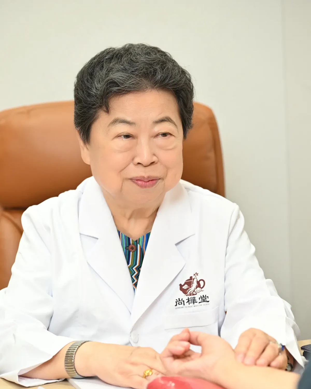 段玉華醫師身穿尚樺堂中醫診所白袍,在診所內的肖像照